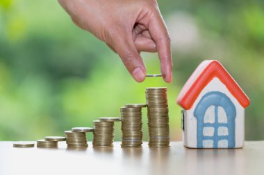 Yığın altın sikke ve ev modeli, yeni ev ve Yatırım Emlak konsepti ile satın almak için para tasarrufu tutan bir erkek el.