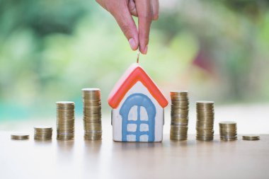 Yığın altın sikke ve ev modeli, yeni ev ve Yatırım Emlak konsepti ile satın almak için para tasarrufu tutan bir erkek el.