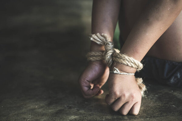 Victim boy with hands tied up with rope in emotional stress and pain,  kidnapped, abused, hostage,  afraid, restricted, trapped,  struggle,  Stop violence against children and trafficking Concept.