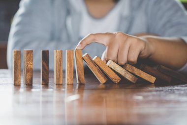  İşadamı el durdurma düşen tahta domino etkisi sürekli devrildi veya risk, strateji ve iş, oyun strateji, yatırım ve Risk yönetimi için başarılı müdahale kavramı.