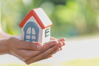 Yatırımcı göstermek bir model ev tutan el ve madeni para, yeni bir ev satın almak için para tasarrufu ve kredi planı iş yatırım emlak gelecekteki kavram için için.