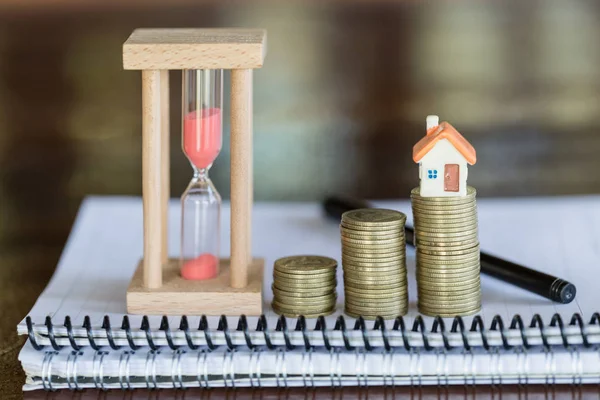 Mini house on stack of coins,Money and house,  Mortgage, Savings money for buy house and loan to business investment for real estate concept. Invesment and Risk Management, hourglass.