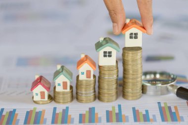 İnsan eli ev modeli belirli bir konuma geçirme yığını bozuk paralar. Konsept Emlak merdiven, ipotek ve gayrimenkul yatırım için