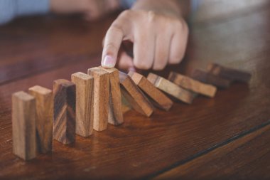  İşadamı el durdurma düşen tahta domino etkisi sürekli devrildi veya risk, strateji ve iş, oyun strateji, yatırım ve Risk yönetimi için başarılı müdahale kavramı.