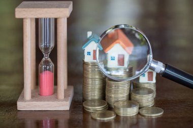 Minyatür evin büyüteç ve madeni para, ipotek, Kiralık Konut, ev arama kavramı İnşaat için konum seçimi.  
