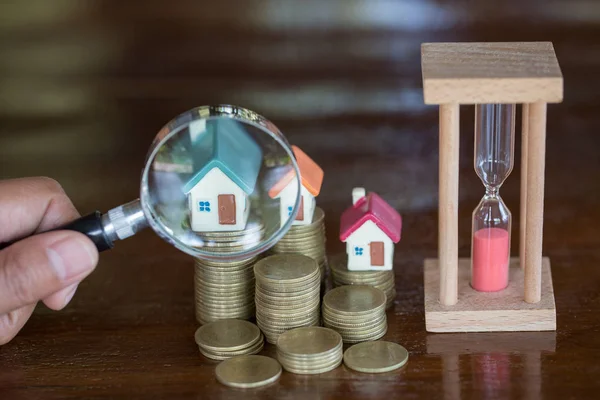 Stack coin and bar graph with grow,  Hand hold a magnifying glass searching for a new home, Loan for real estate or save money for buy a house to family in the future concept.