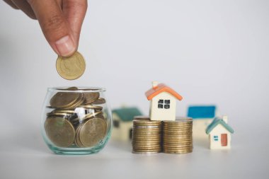 Yığın altın sikke ve ev modeli, yeni ev ve Yatırım Emlak konsepti ile satın almak için para tasarrufu tutan bir erkek el.