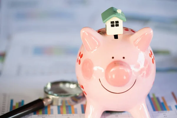 A house model placed on a piggy bank, finance and banking,  Saving money and property Management concept.
