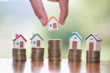 İnsan eli, ev modelini madeni paraların üzerine koyar, ev konsepti, ipotek ve emlak yatırımı almak için madeni paralardan tasarruf parası planlar. Bir ev için tasarruf veya yatırım.