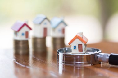 Minyatür evin büyüteç ve madeni para, ipotek, Kiralık Konut, ev arama kavramı İnşaat için konum seçimi.  