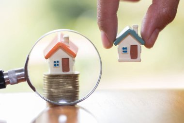Minyatür evin büyüteç ve madeni para, ipotek, Kiralık Konut, ev arama kavramı İnşaat için konum seçimi.  