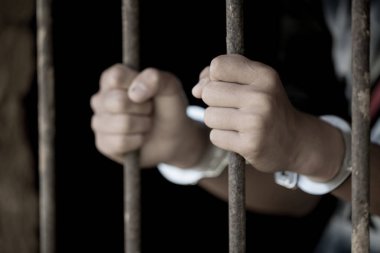 Adam hapiste eller tutun çelik kafes hapsi barlar, Erkek mahkumlar ciddi gergin karanlık hapishane, hapis, şiddet, insan kaçakçılığı, hapishane ve mahkum kavramı.