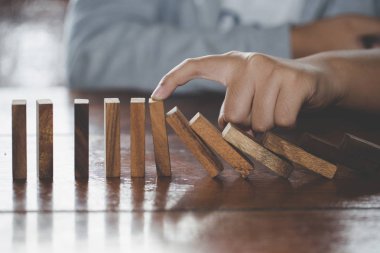  İşadamı el durdurma düşen tahta domino etkisi sürekli devrildi veya risk, strateji ve iş, oyun strateji, yatırım ve Risk yönetimi için başarılı müdahale kavramı.