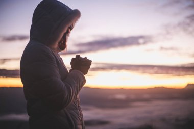 Güneş doğarken, Christian Religion kavramı arka plan Tanrı'ya dua genç insan eli silüeti.