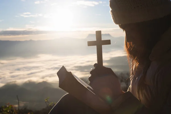 光夕日を背景にキリスト教の十字の神聖なリフトを持つ女性の手のシルエット — ストック写真