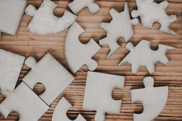Wooden jigsaw puzzle is placed on an old wooden table.