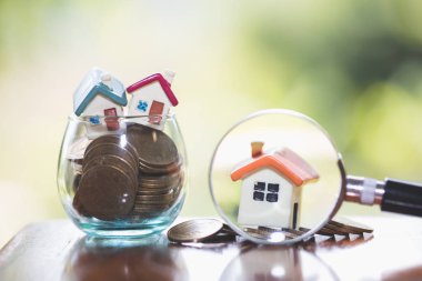 bir ipotek, bir sikke, bir model bir ev ve bir büyüteç, ev ve para kavramı. Büyüteç ve paralar, inşaat, Kiralık Konut. 