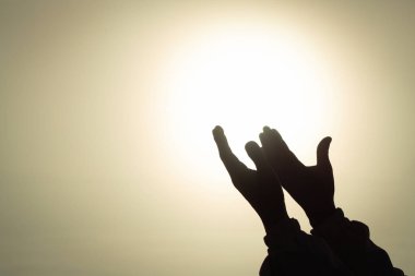 Genç insan ellerinin silueti avuçlarını açar gündoğumunda Tanrı 'ya dua eder ve dua eder, Hıristiyan dini kavramının arka planı.