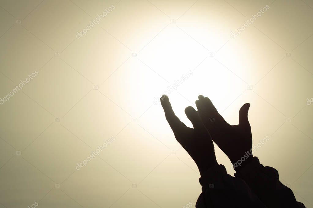 Silhouette of young  human hands open palm up worship and praying to god  at sunrise, Christian Religion concept background.