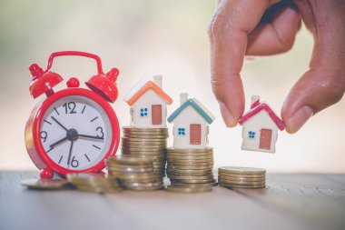 Kadın elini tut büyüyen ile yığın para koymak bir ev modeli