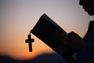 Kadın dua Tanrı İncil ve sabah çapraz ile el