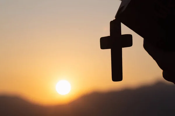 Silhouette of Young woman hands holding holy Bible and lift of c