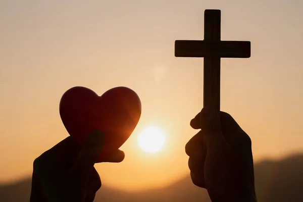 Silhouette of woman hands praying with cross and holding a red h — Stock Photo, Image