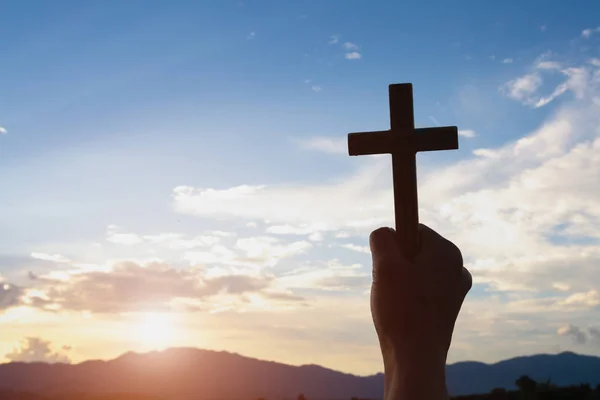 Ženská ruka drží Svatý pozvednout křesťanské kříže s světle sunse — Stock fotografie