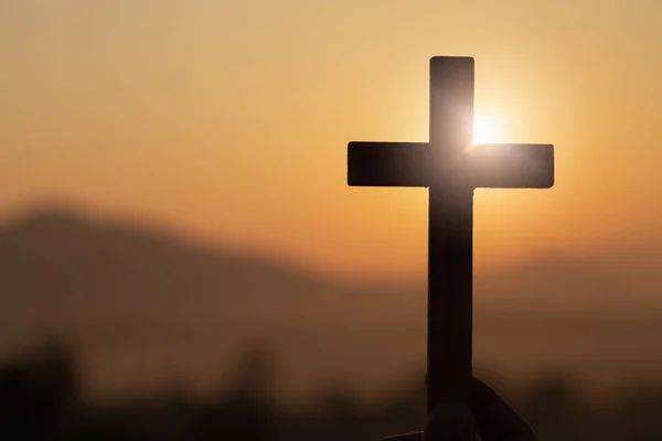 Silueta de manos de mujer joven sosteniendo el levantamiento de la cruz cristiana — Foto de Stock