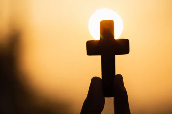 Silhueta de mãos de mulher orando com cruz na natureza nascer do sol — Fotografia de Stock