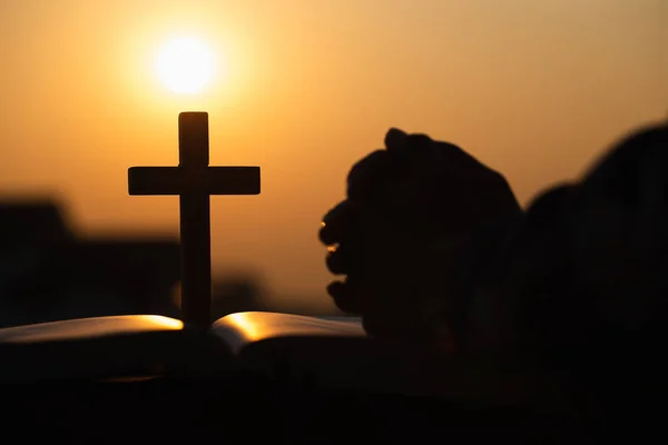 Silueta křesťanské mladé ženy modlící se křížkem a — Stock fotografie