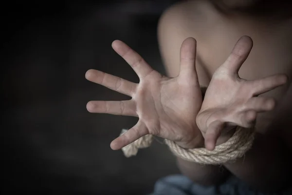 Child abuse, victim boy with hands tied up with rope in emotiona