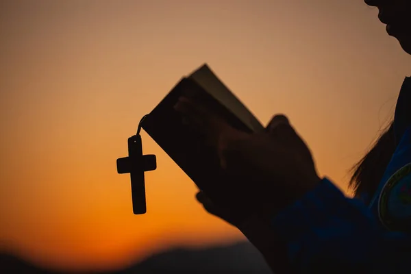 woman holding a holy bible and cross in her hands and praying