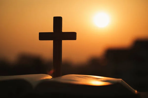 Silueta de la cruz de madera sobre la biblia abierta con una s brillante — Foto de Stock