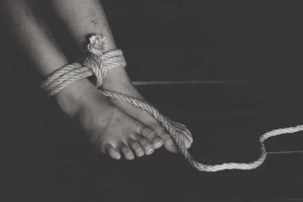 Feet of a missing kidnapped, abused, hostage, victim woman tied up with rop...