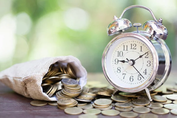 Alarm clock and a pile of golden coins on the table, Concept of — Stock Photo, Image