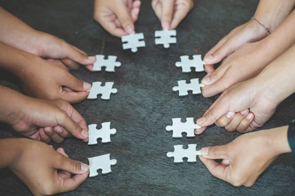 Mani di persone diverse assemblaggio puzzle, squadra mettere pezzo — Foto Stock