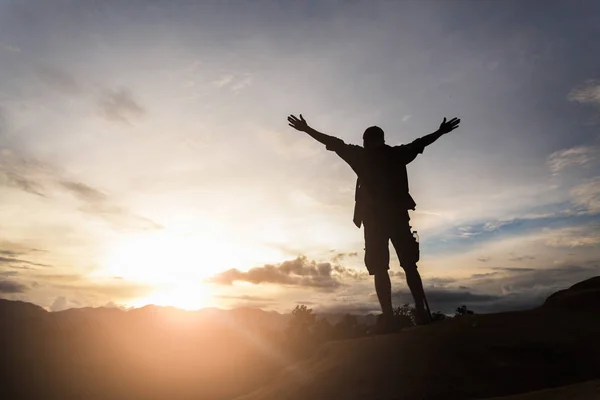 Silhouette eines Wanderers, der auf einem Hügel steht und den Sonnenaufgang genießt — Stockfoto