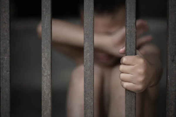 The child sat crying in a dark room separated by a steel cage. T — Stock Photo, Image