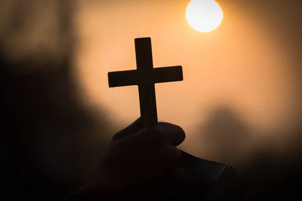 La mano humana sostiene la cruz y la Biblia, la adoración, los pecados y la oración, Reli — Foto de Stock