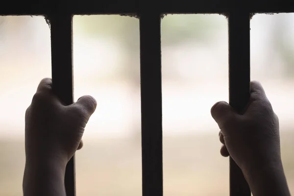 Руки маленького ребенка, хватающегося за тюремные решетки, ребенок-жертва с — стоковое фото
