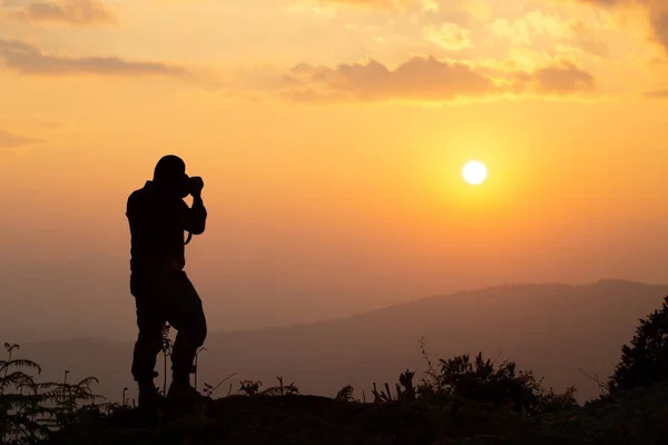 Silhouette of a nature photographer who shoots a sunset and beau — Stock Photo, Image