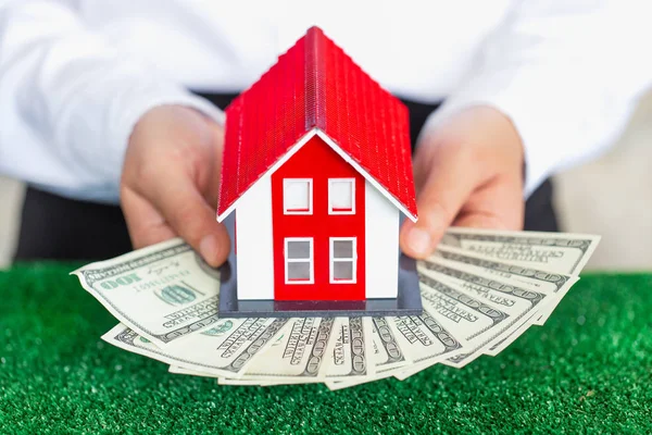 Businessmen holding money and red house models. Real estate loan
