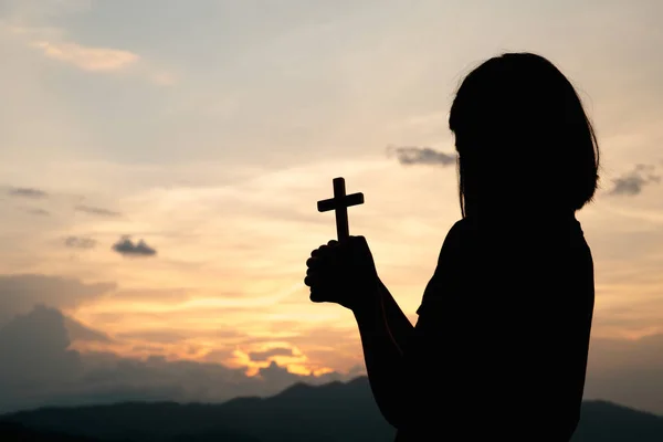 Silhueta de uma jovem segurando um crucifixo para Deus Manhã sagacidade — Fotografia de Stock
