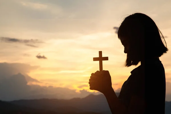 Religious concepts. Silhouette of a girl holding a crucifix to G — Stock Photo, Image