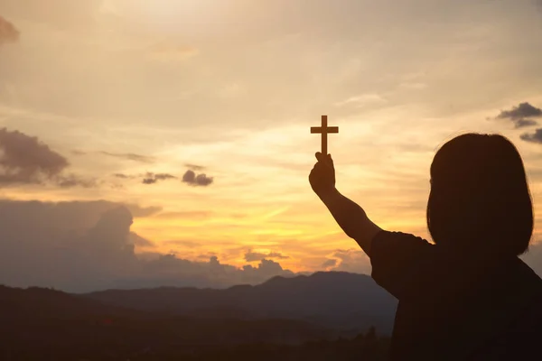 Mão de uma menina segurando uma cruz ao nascer do sol, Eucaristia Terapia Ble — Fotografia de Stock