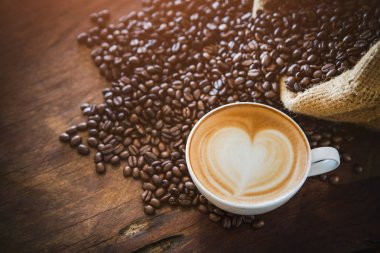 Kahveli latte, kahve çekirdekleri koyu arka planda, manzaralı.