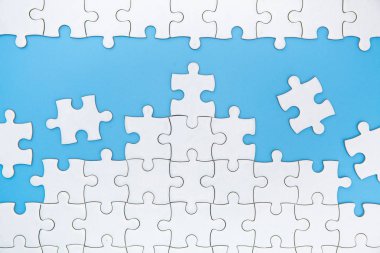 Mavi arka planda tamamlanmamış beyaz puzzle parçaları, La