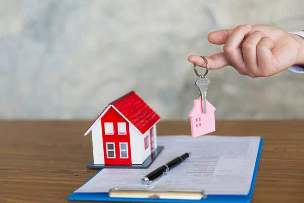 real estate agent holding house key to his client after signing