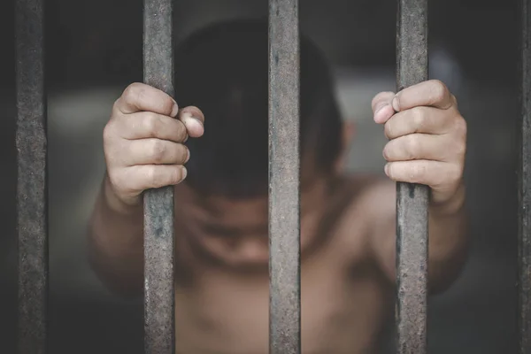 Hands of a young child clutching prison bars, victim child with — Stock Photo, Image
